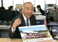 タイで建てた小学校の写真を見せながら活動の様子を話す谷川洋さん＝東京都港区で