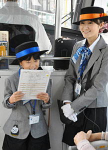 制服を着て車内アナウンスをする参加者（左）＝富山市で
