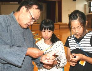 渡辺さん（左）と穂が真っすぐ差し込まれているか確認する子どもたち＝大府市共和西小で