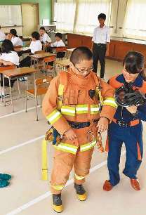 防火衣を消防士（右）に着せてもらう生徒