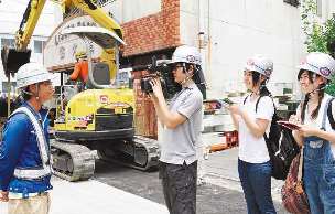 水道管の取り換え工事を撮影する名古屋ビジュアルアーツの社本さん（左から２人目）、宮田さん（右から２人目）ら生徒＝名古屋市名東区で