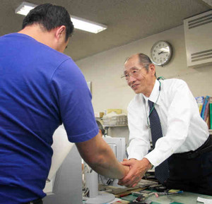 帰国を決めた日系ブラジル人男性（左）と握手を交わす井口相談員＝伊那市のハローワーク伊那で