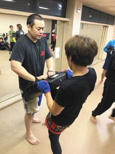 工場を退社後、経営するキックボクシング教室で生徒の蹴りを受ける＝三重県多気町で