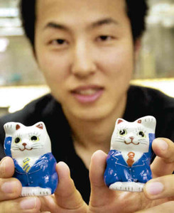 青いスーツ姿の招き猫を企画、商品化した広記さん＝能美市泉台町の北野陶寿堂で
