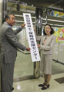 看板を掲げる牛嶋早苗県少子化対策監(右)と県社会福祉協議会の西尾昭雄専務理事＝名古屋市中区の県社会福祉会館で