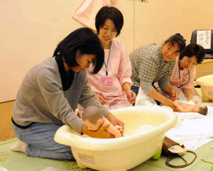 助産師の仕事を体験する参加者＝津市の県総合文化センターで