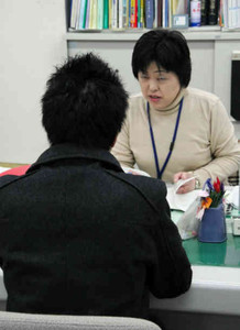 障害者を対象とした求人情報を閲覧し、職員に相談する男性＝長野市のハローワーク長野で