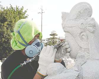 観音像の顔を削り出す小野直行さん＝岡崎市の小野石材店で