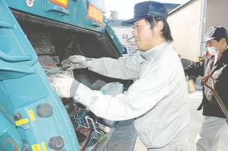 収集車にごみ袋を次々と投入していく清水浩之さん＝豊橋市内で