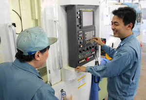 金属を削る大型機械の使い方の指導を受ける受講生＝越前市の福井職業能力開発促進センターで