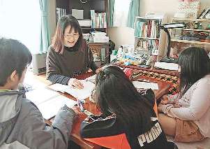 子どもに計算を教える武山さん。津波で泥をかぶり、使えなくなった家具やストーブは、友人らが代わりの品を送ってくれた＝宮城県東松島市で