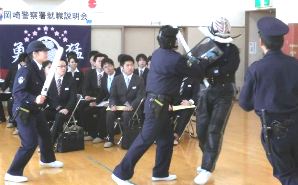 警察官志望者たち（奥）を前に、迫真の逮捕術実演を繰り広げる若手警察官ら＝岡崎署で