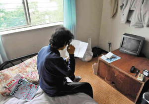 失業者用の宿泊施設で、生活保護受給の通知書を読む４０代男性＝９日、名古屋市緑区で