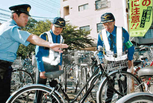警察官（左）の指導を受け、盗難自転車がないか確認する警備員＝津市で