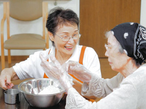 デイサービス利用のお年寄りとおやつ作りをする柳堀幸枝さん（左）＝東京都江東区で