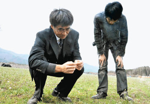 土の様子を確かめる佐藤さん（左）＝伊那市西箕輪の牧草地で