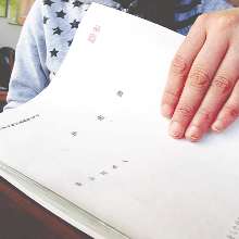 愛知労働局から届いた決定書を開く女性。後遺症で時折、手が震える＝名古屋市内で