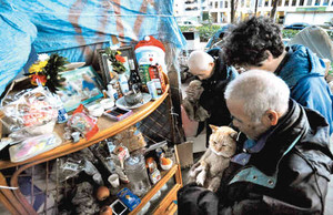 祭壇に手を合わせる仲間や支援者ら。手前のネコは生前飼っていたテツ＝名古屋市千種区で