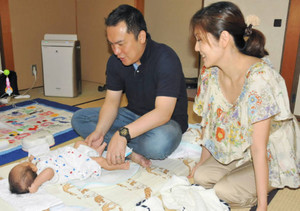 育休中に長男・結大君の世話をする鈴木知事（左）。隣は妻の美保さん＝津市観音寺町の知事公舎で