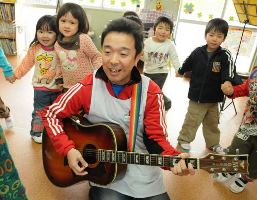 得意のギターを手に園児たちと触れ合う浦田裕人さん＝名古屋市南区豊の明治保育園で