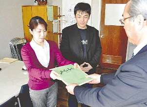 北沢明校長に「みちしるべ」を手渡す（左から）熊谷さんと知久さん＝飯田市の飯田東中学校で