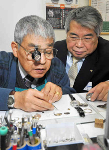 時計修理職人の作業を見守る瀬口良人社長（右）＝愛知県清須市のジェムウォッチ須ケ口駅店で